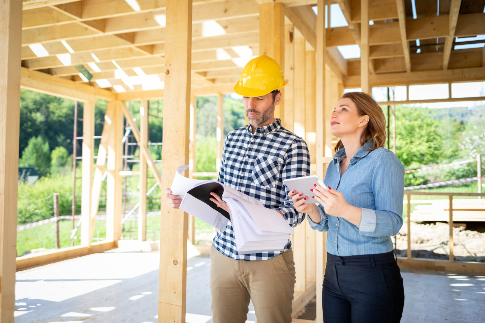 Architect or engineer with blueprints meeting with owner of building house on construction site