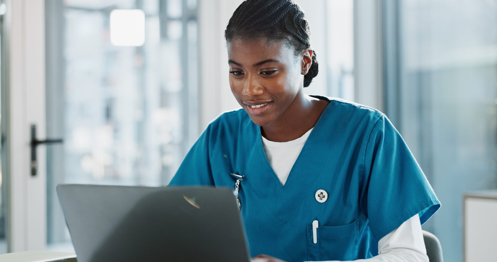 Clinic, doctor and black woman with laptop, typing and thinking with research, online reading and network African person, medical or happy professional with computer, nurse or connection in hospital